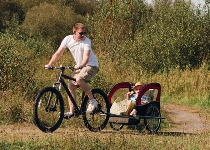 Man Cycling With Child In Trailer On Path jlthtv