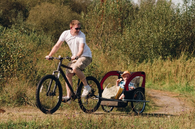 Man Cycling With Child In Trailer On Path jlthtv