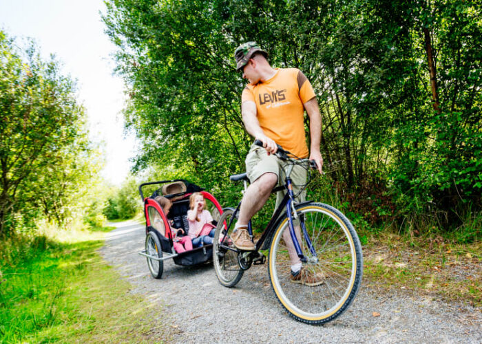 Man cycling with children in bike trailer g4vdhf