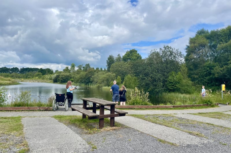 People Fishing By A Lake With Picnic Table