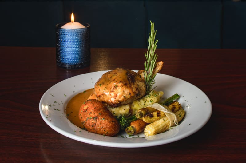 Roasted chicken meal with vegetables and lit candle