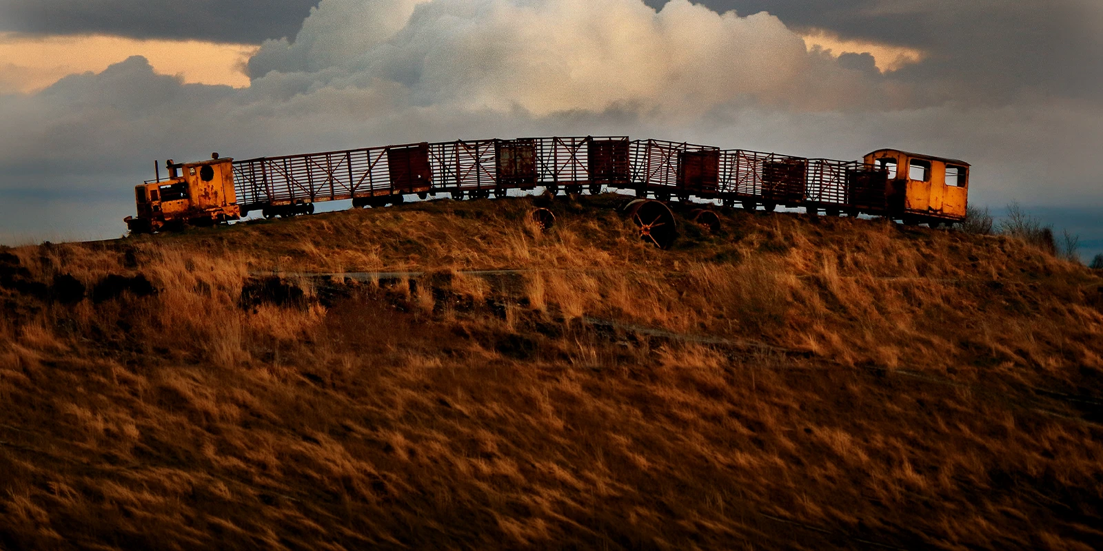 Old rusted abandoned train arching over hill in the sunset