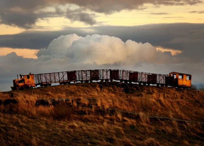 Old rusted abandoned train arching over hill in the sunset