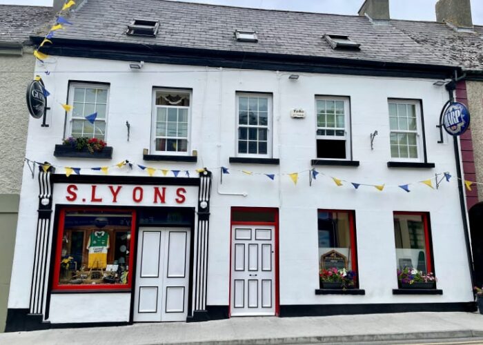White building with S Lyons shopfront and bunting