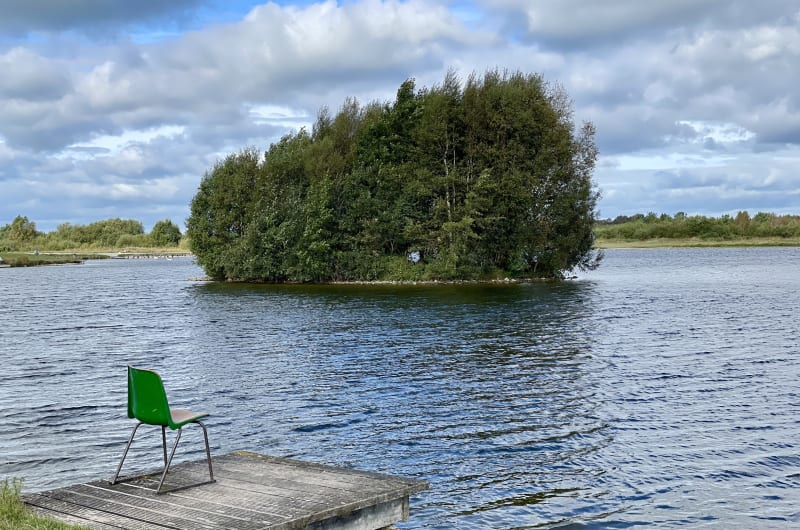 Wooden dock with green chair overlooking tree island