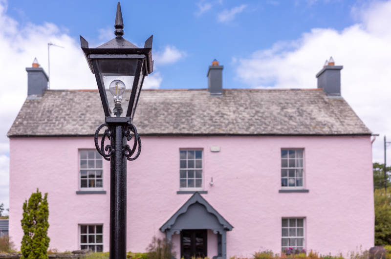 black lamp post with pink house behind