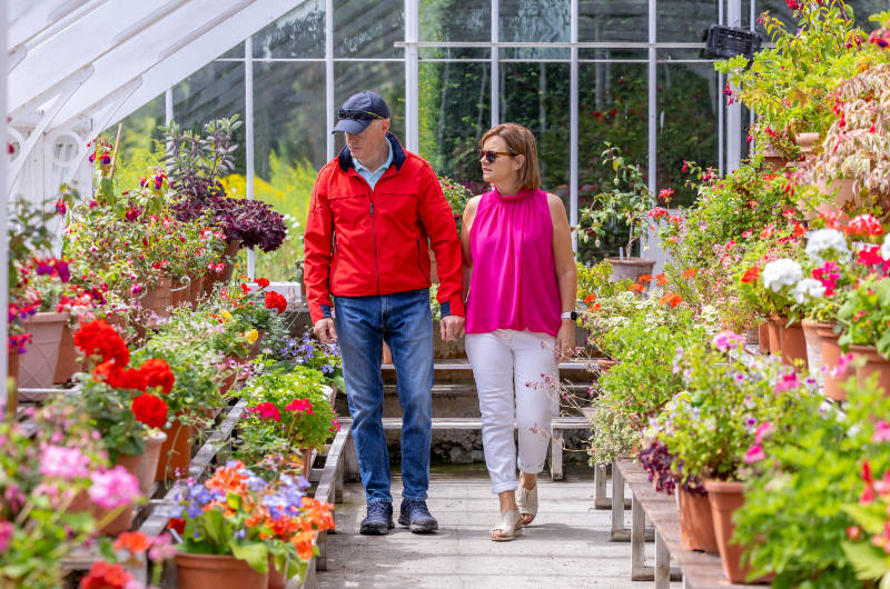 man and woman walking through garden centre green house