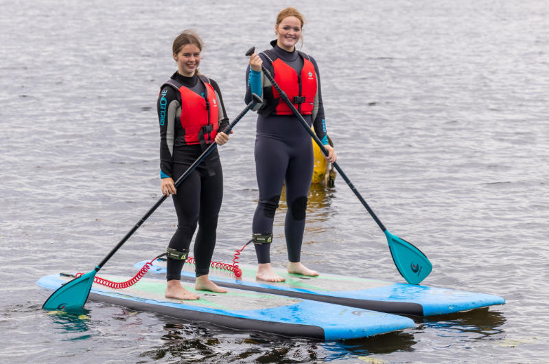two girls surf boards oars