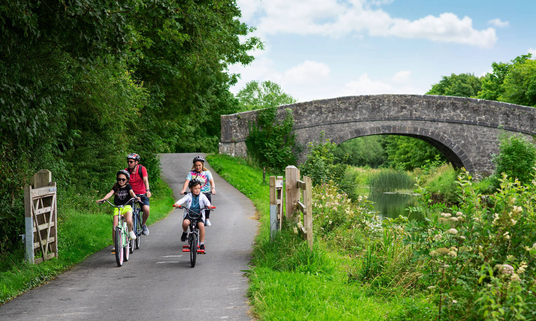 hero family cycling by river stone bridge in background