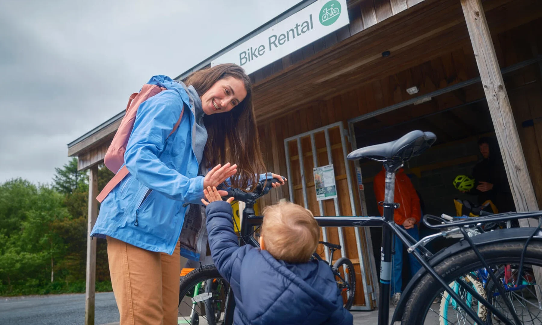 Woman and child high fiving in front of bike rental shack